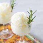 Glass with a scoop of sorbet garnished with a rosemary sprig.