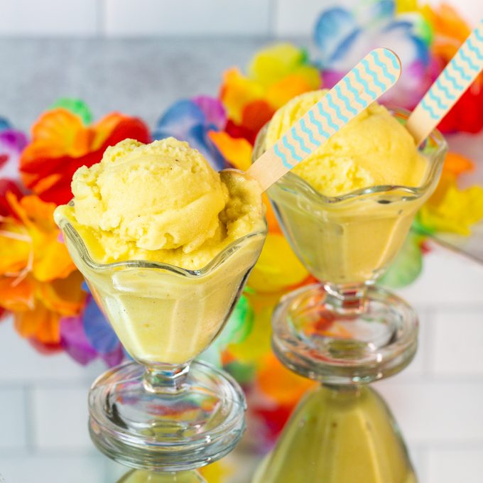 Two sundae glasses filled with a bright yellow sorbet.