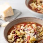 Bowl of minestrone soup garnished with Parmesan Cheese.