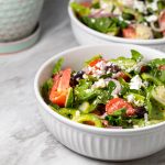 Greek salad in a white bowl.