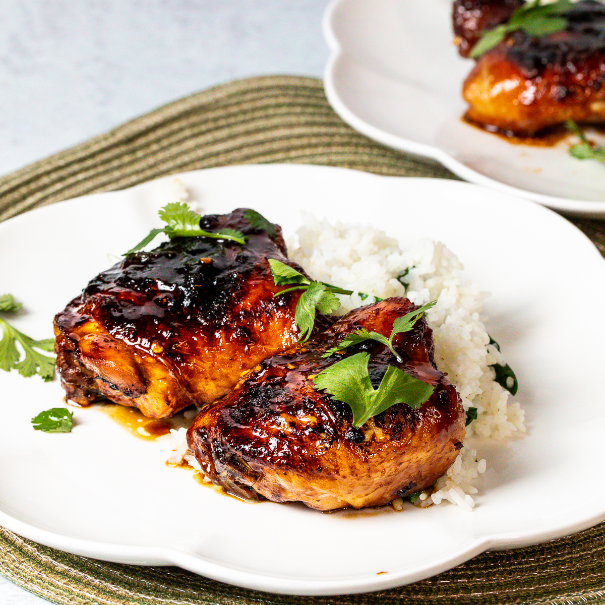 Two sticky Thai Chicken thighs on a plate.