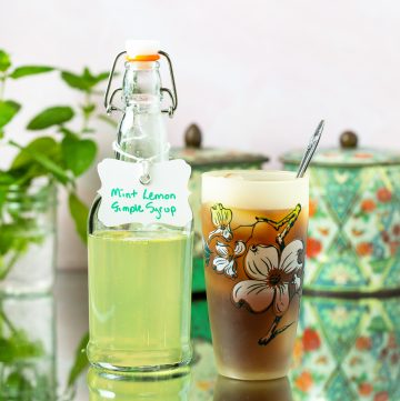Mint Lemon Simple Syrup in a bottle next to a glass of iced tea.