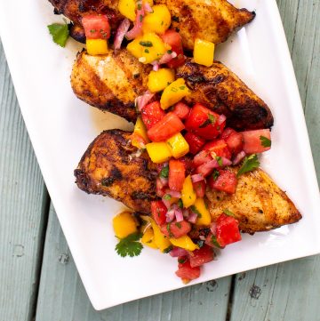 Plate of grilled chicken topped with a mango watermelon salsa.