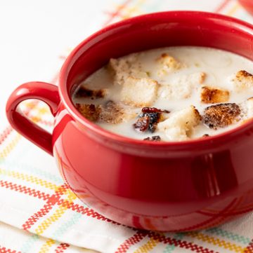 Red bowl filled with potato leek soup.