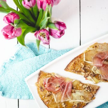Pizza on a white plate with a vase of flowers.