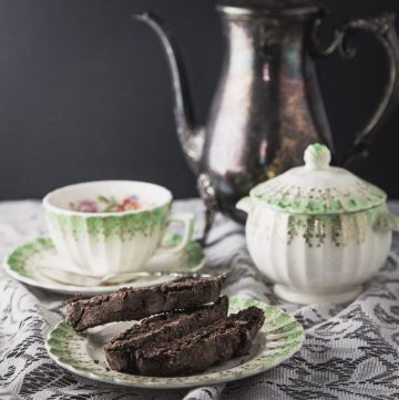 Plate of biscotti in front of a teacup and sugar bowl.