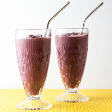 Two glasses filled with a purple smoothie.