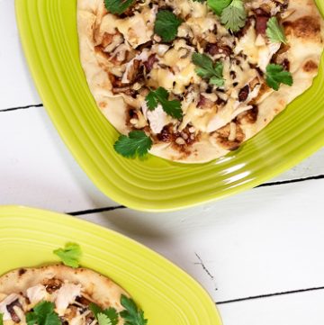 Naan flatbread pizza on a white plate.