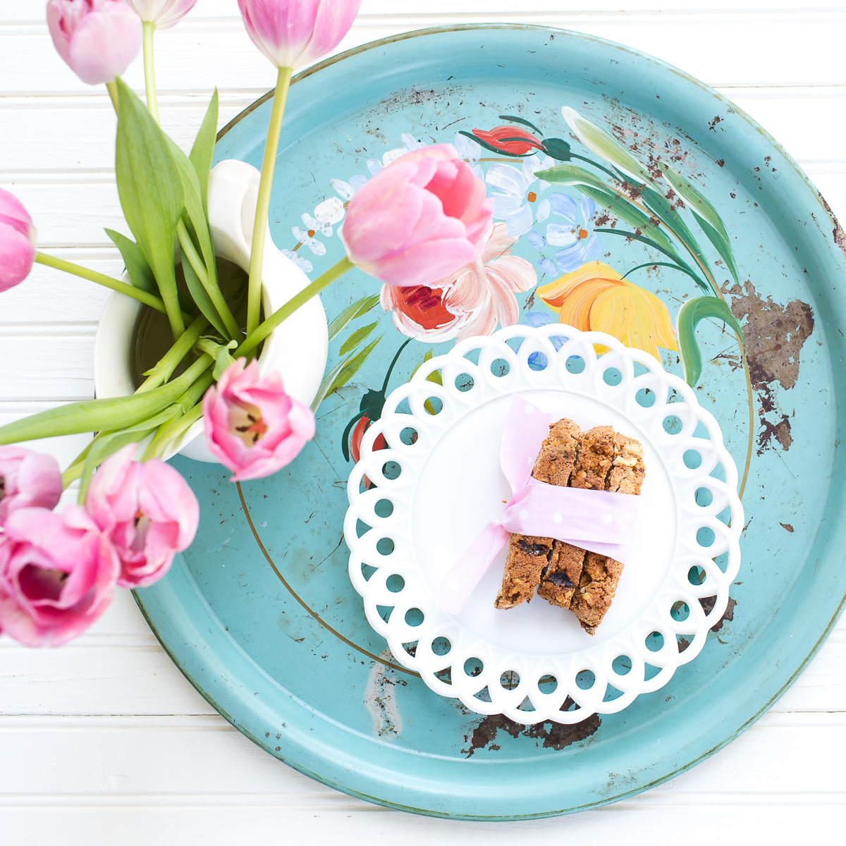 Blue tray with a plate of biscotti and vase of tulips.