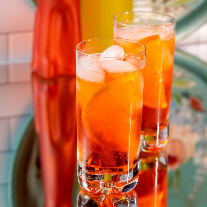 Two glasses filled with a bright orange cocktail.