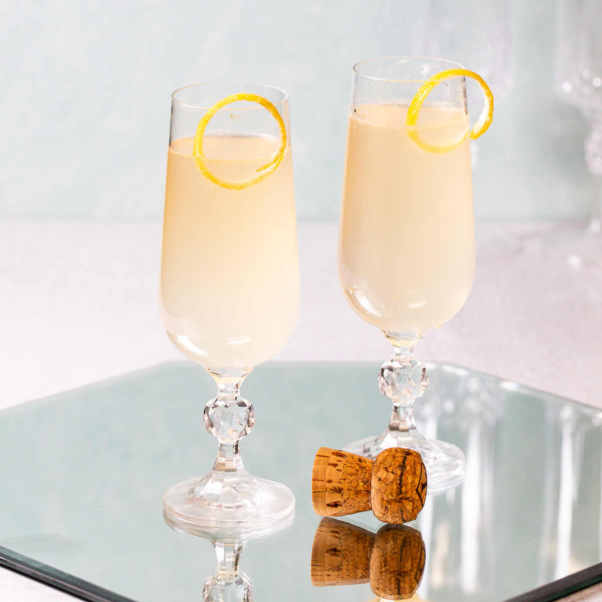 Two sparkling cocktails with a popped champagne cork.