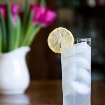 Tom Collins Cocktail in front of a vase of flowers