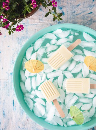 Piña Colada popsicles on a blue ice filled tray.
