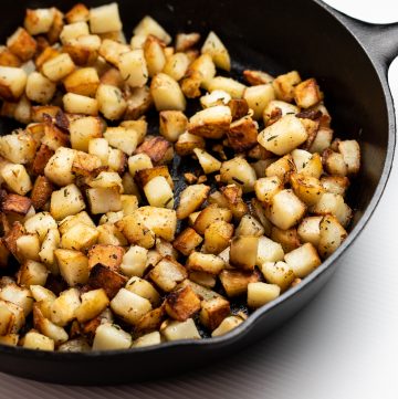 Golden brown potatoes in a cast iron skillet.