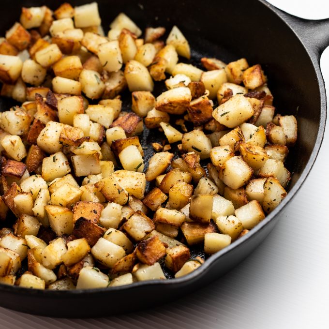 Golden brown potatoes in a cast iron skillet.