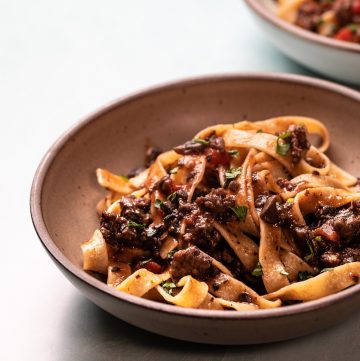 Bowl of pasta topped with mushroom and sausage ragu.