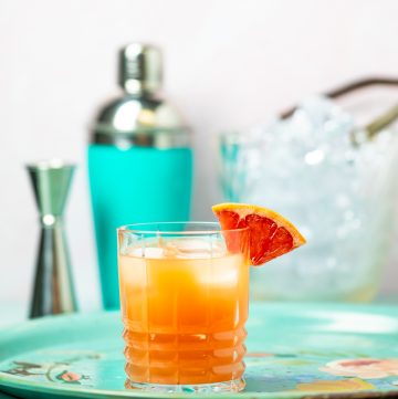 Orange cocktail garnished with a grapefruit wedge.