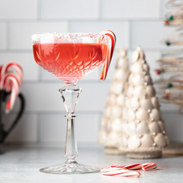 Peppermint martini in front of small white Christmas trees.