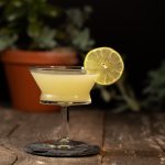 Yellow cocktail garnished with a lime wheel.