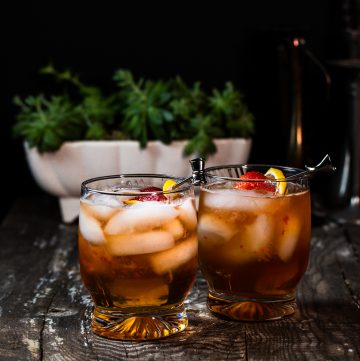 Two cocktails garnished with strawberries and lemon.