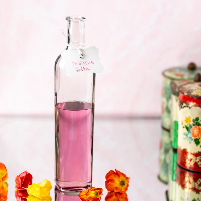Bottle filled with pink liquid and labeled hibiscus vodka.
