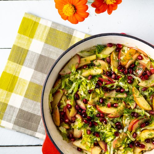 Apples and cabbage in a red skillet.