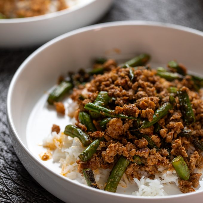 White bowl with ground pork and green beans.