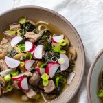 Bowl of pork noodle soup topped with radishes and green onions.