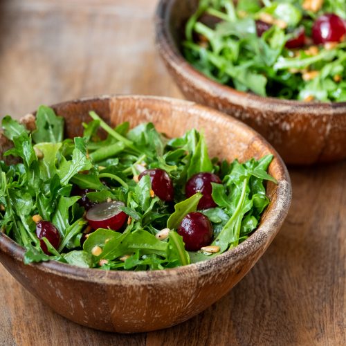 Two wooden salad bowls filled with salad.