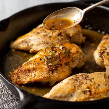 Chicken breasts with sauce being spooned on.