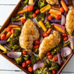 Close up of chicken and vegetables on a sheet pan.