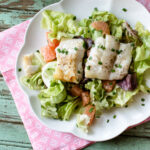 Cod salad with grapefruit on a white plate.