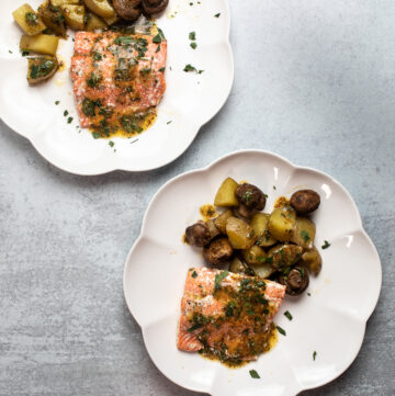 Two plates with salmon, potatoes and mushrooms.