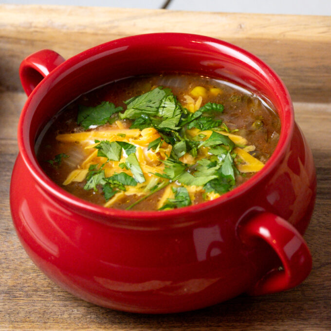 Close up of chicken tortilla soup in a red bowl.