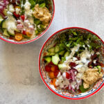 Two bowls with toppings of peppers, sauce, tomatoes, cilantro and more.