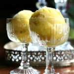 Close up of mango sorbet in two antique glasses.