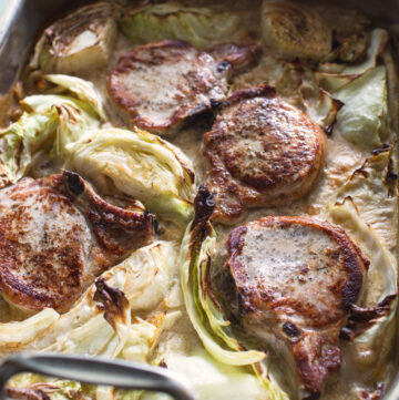 Close of of browned pork chops on a bed of creamy cabbage.