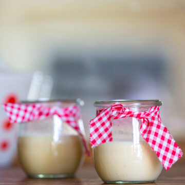 Two jars of eggnog panna cotta with bows on them.