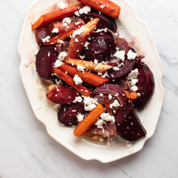 Close up of roasted root vegetables with goat cheese on top.
