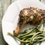 Roast chicken with tarragon pesto on a plate with green beans.