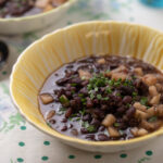 Yellow bowl filled with black bean soup.